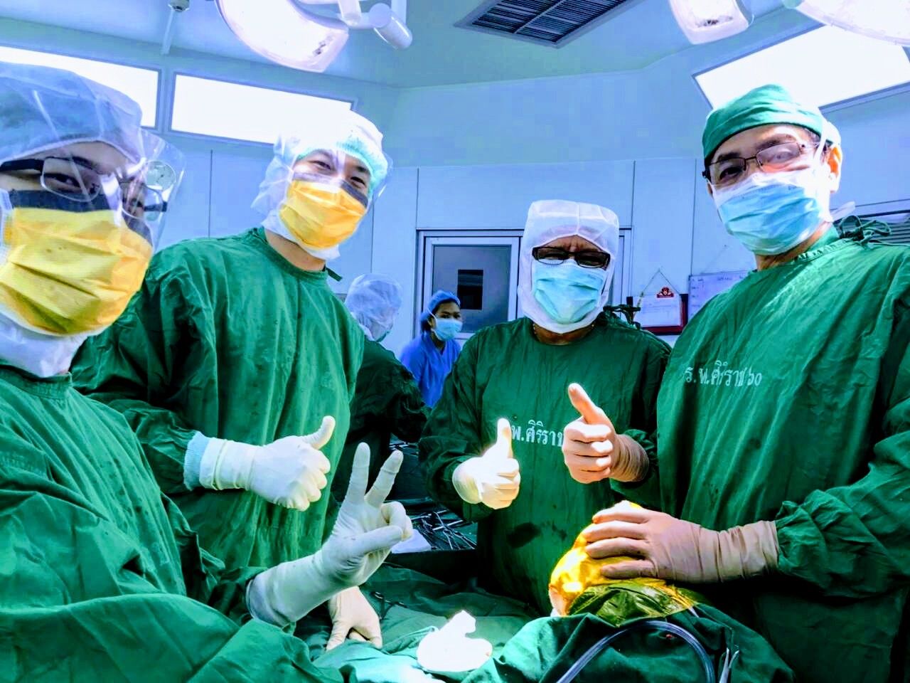 An international surgical team smiling in green scrubs after an operation